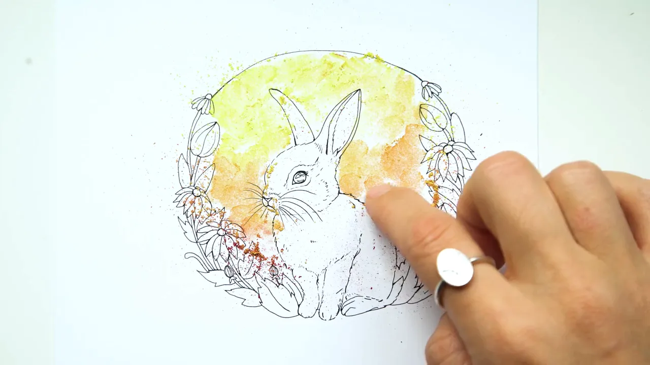 Rachel's hand blending a soft yellow glow behind a bunny line drawing