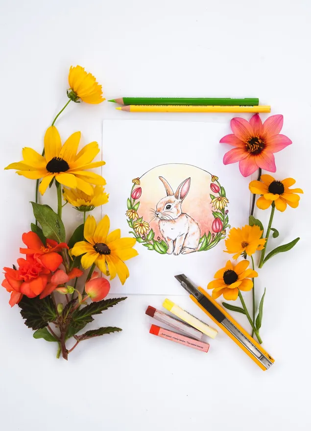 A colored bunny in a wreath of black-eyed Susans with fresh dahlias and pencils