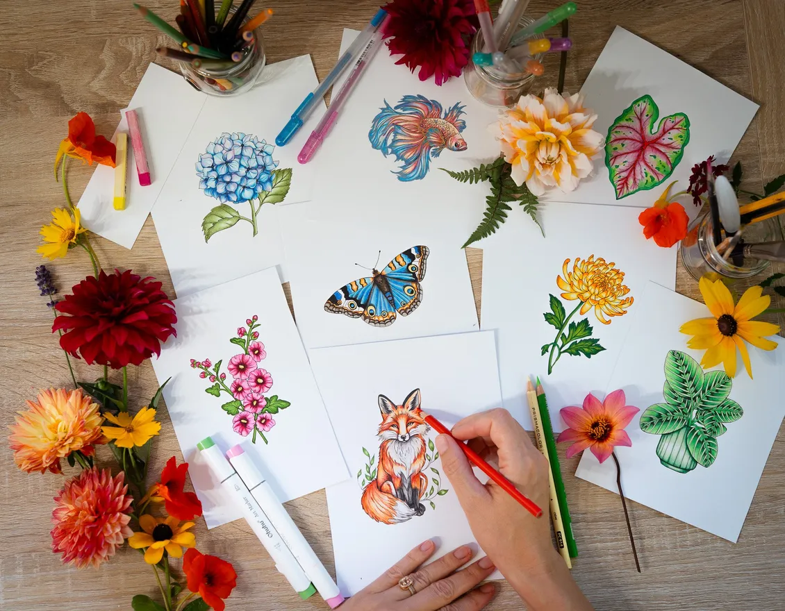 Rachel's hand coloring a red fox among fresh flowers and colored illustrations