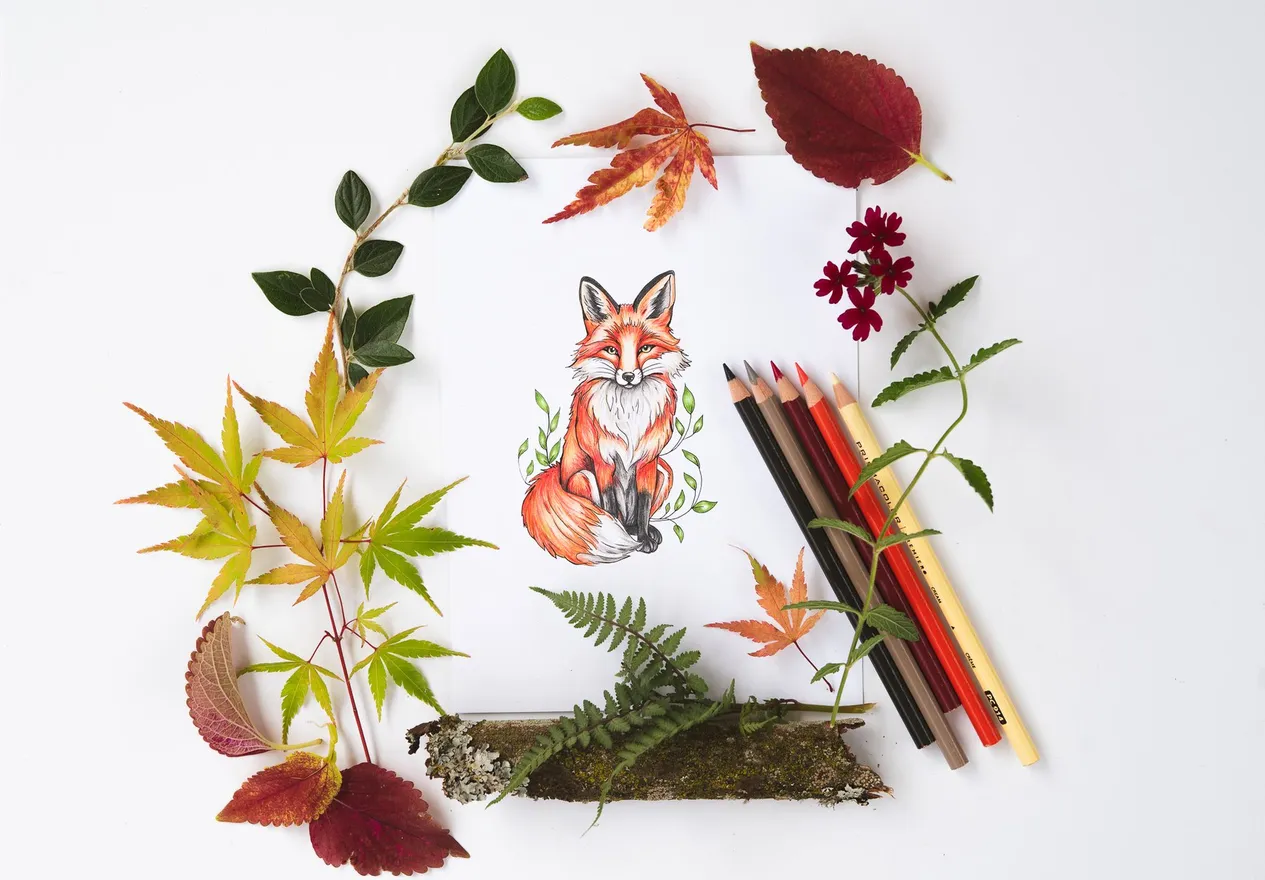A colored fox inside a wreath of autumn leaves with pencils