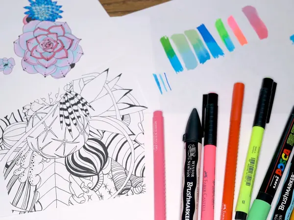 Alcohol markers and color swatches beside a page of succulents