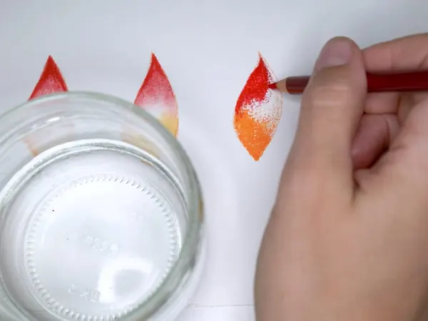Watercolor pencil petals blended with water beside a glass